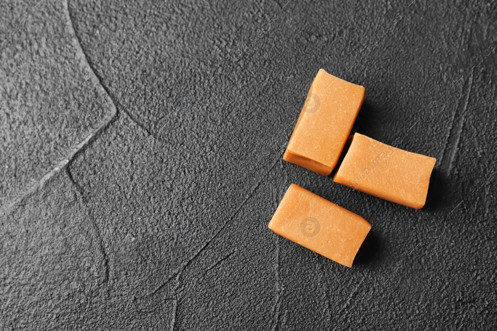 Photo of Delicious caramel candies on dark background, top view