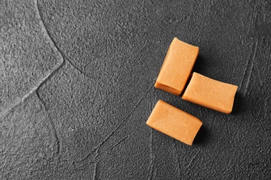 Photo of Delicious caramel candies on dark background, top view