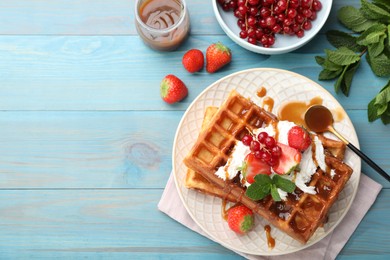 Photo of Delicious Belgian waffles with berries and caramel sauce served on turquoise wooden table, flat lay. Space for text