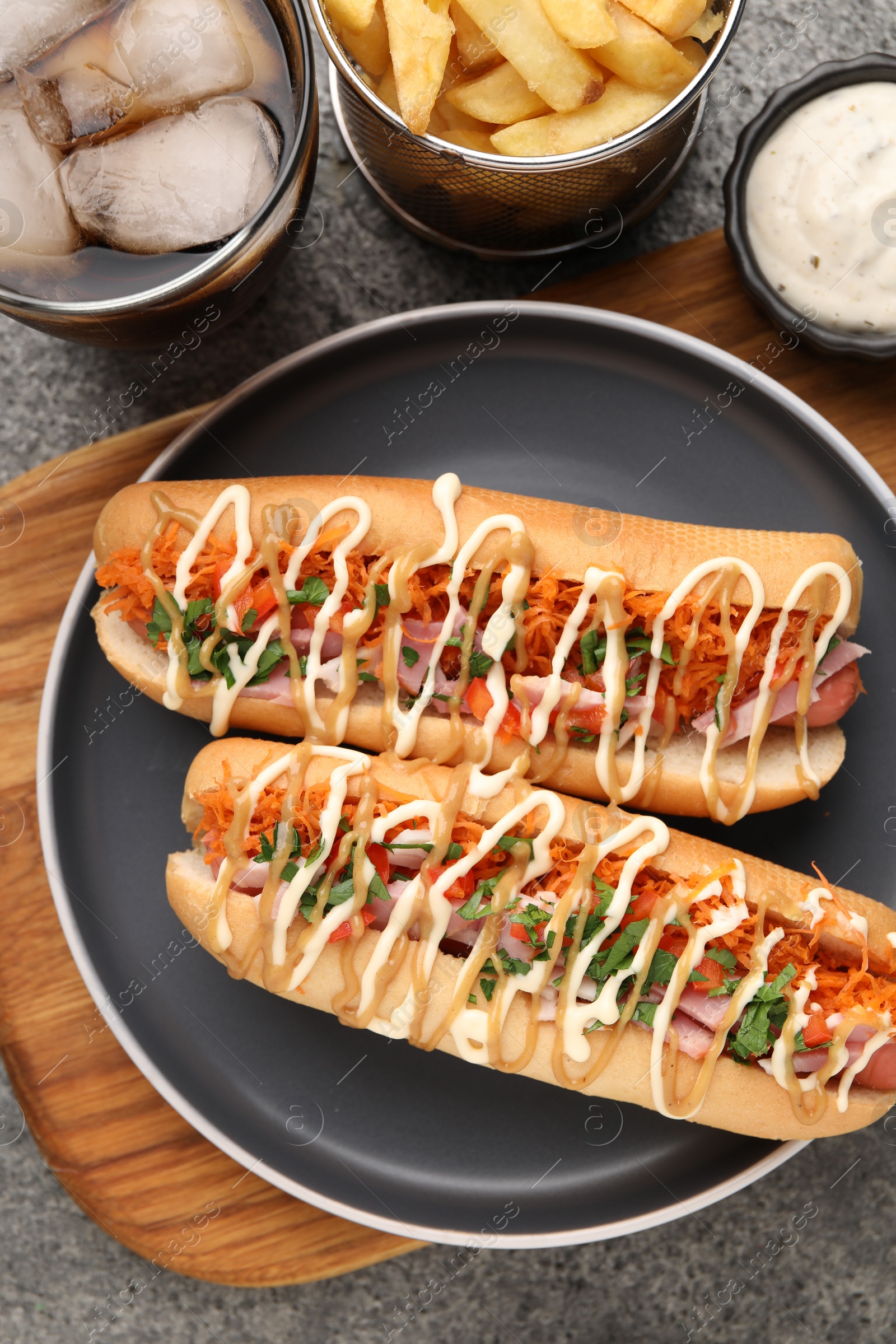 Photo of Delicious hot dogs with bacon, carrot and parsley served on grey table, flat lay