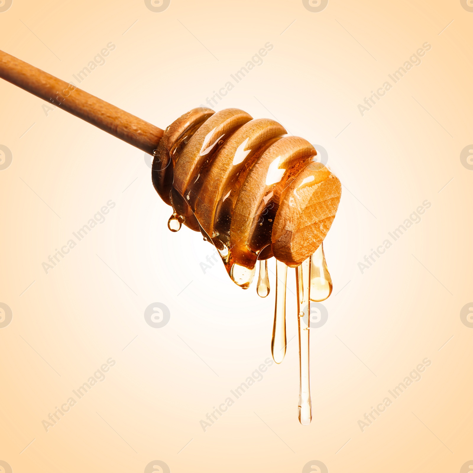 Image of Natural honey dripping from dipper on pale orange background