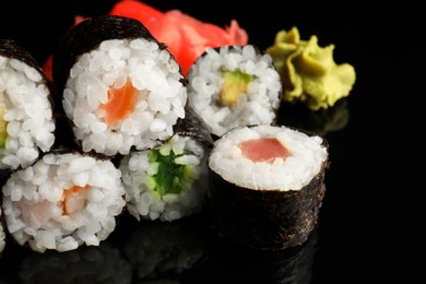 Set of delicious sushi rolls on black background, closeup