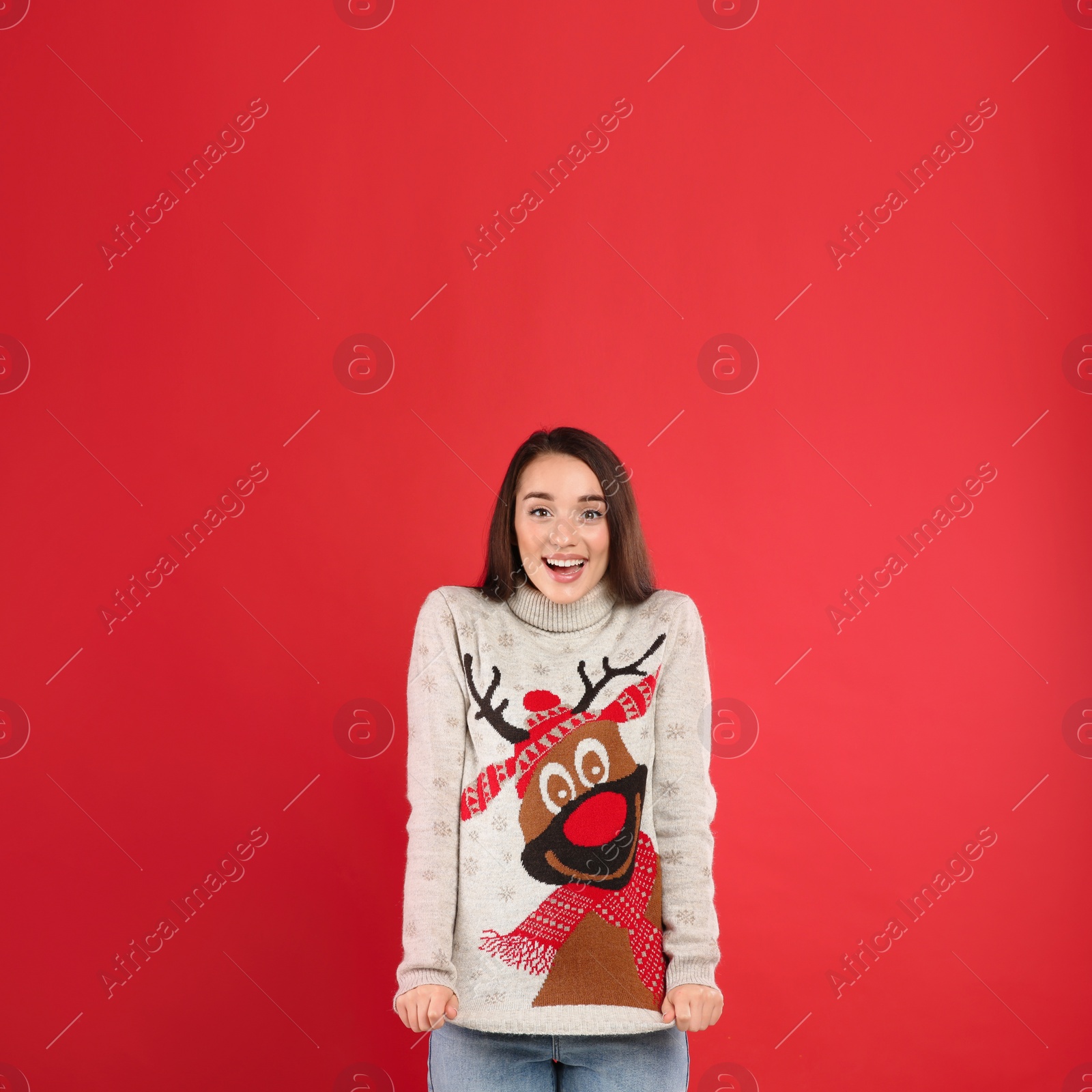 Photo of Young woman in Christmas sweater on red background, space for text