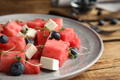 Photo of Delicious salad with watermelon, blueberries and feta cheese on wooden table, closeup