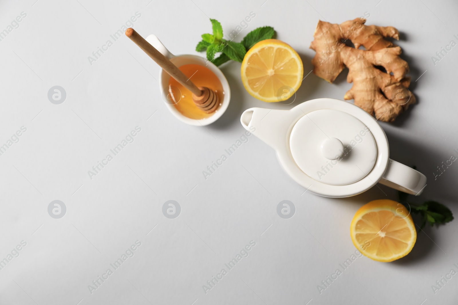 Photo of Delicious ginger tea and ingredients on light grey background, flat lay. Space for text