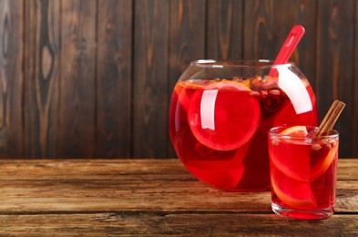 Photo of Glass and bowl with aromatic punch drink on wooden table, space for text