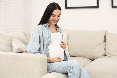 Photo of Happy pregnant woman on sofa at home