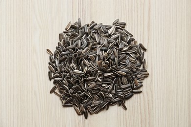 Pile of sunflower seeds on wooden table, flat lay