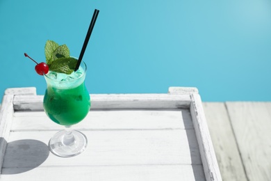 Photo of Refreshing cocktail on wooden table near swimming pool outdoors. Space for text