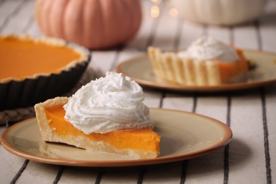 Piece of fresh homemade pumpkin pie with whipped cream on table