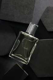 Photo of Stylish presentation of luxury men`s perfume in bottle on black background, top view