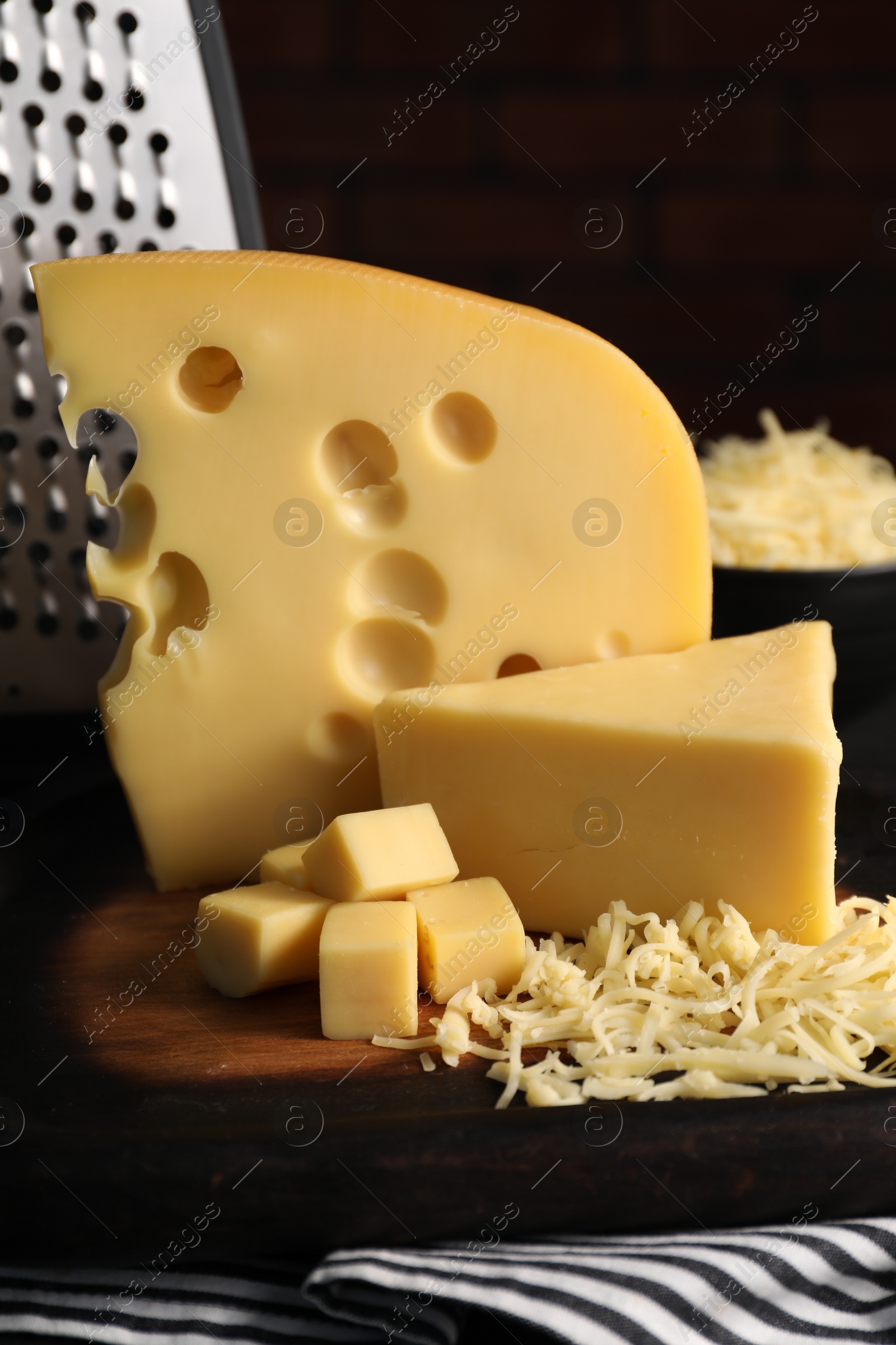 Photo of Grated, cut cheese and grater on table, closeup