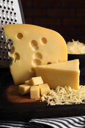 Photo of Grated, cut cheese and grater on table, closeup