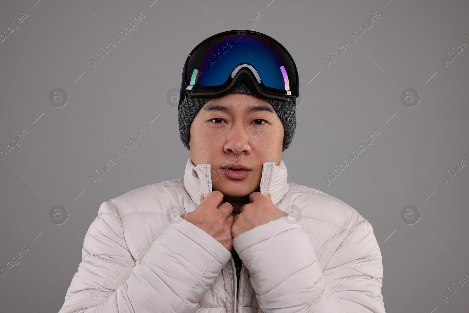 Photo of Winter sports. Man with ski goggles on grey background