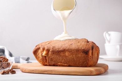 Photo of Pouring cream onto sweet cake on white table
