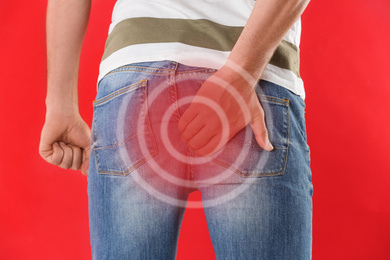 Image of Man suffering from hemorrhoid on red background, closeup
