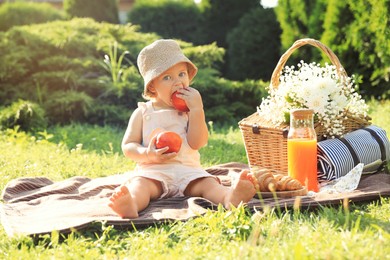 Cute little baby girl with nectarines on picnic blanket in garden
