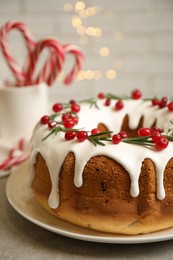 Photo of Traditional Christmas cake with cranberries, pomegranate seeds and rosemary on light grey table, closeup