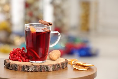 Photo of Aromatic mulled wine in glass cup on wooden table against blurred background. Space for text