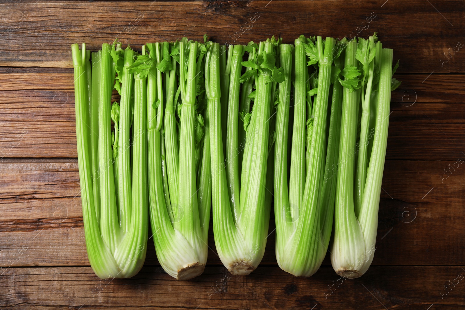 Photo of Fresh ripe green celery on wooden table, flat lay