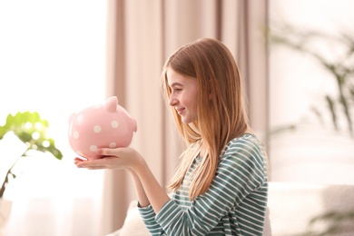 Teen girl with piggy bank at home