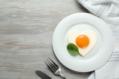 Tasty breakfast with heart shaped fried egg served on white wooden table, flat lay. Space for text