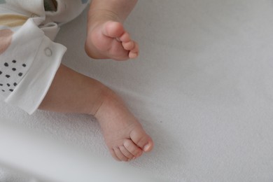 Photo of Cute little baby lying in crib, closeup. Space for text