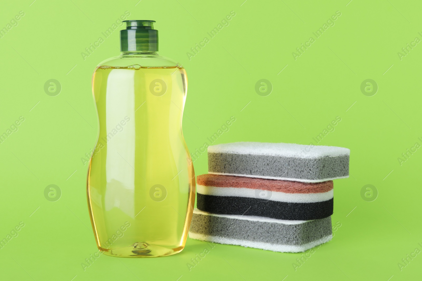 Photo of Cleaning detergent and sponges on green background