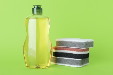 Cleaning detergent and sponges on green background