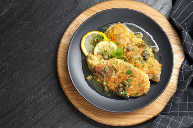 Delicious chicken piccata on black table, top view