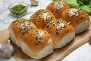 Photo of Traditional pampushka buns with garlic and herbs on white marble table, closeup
