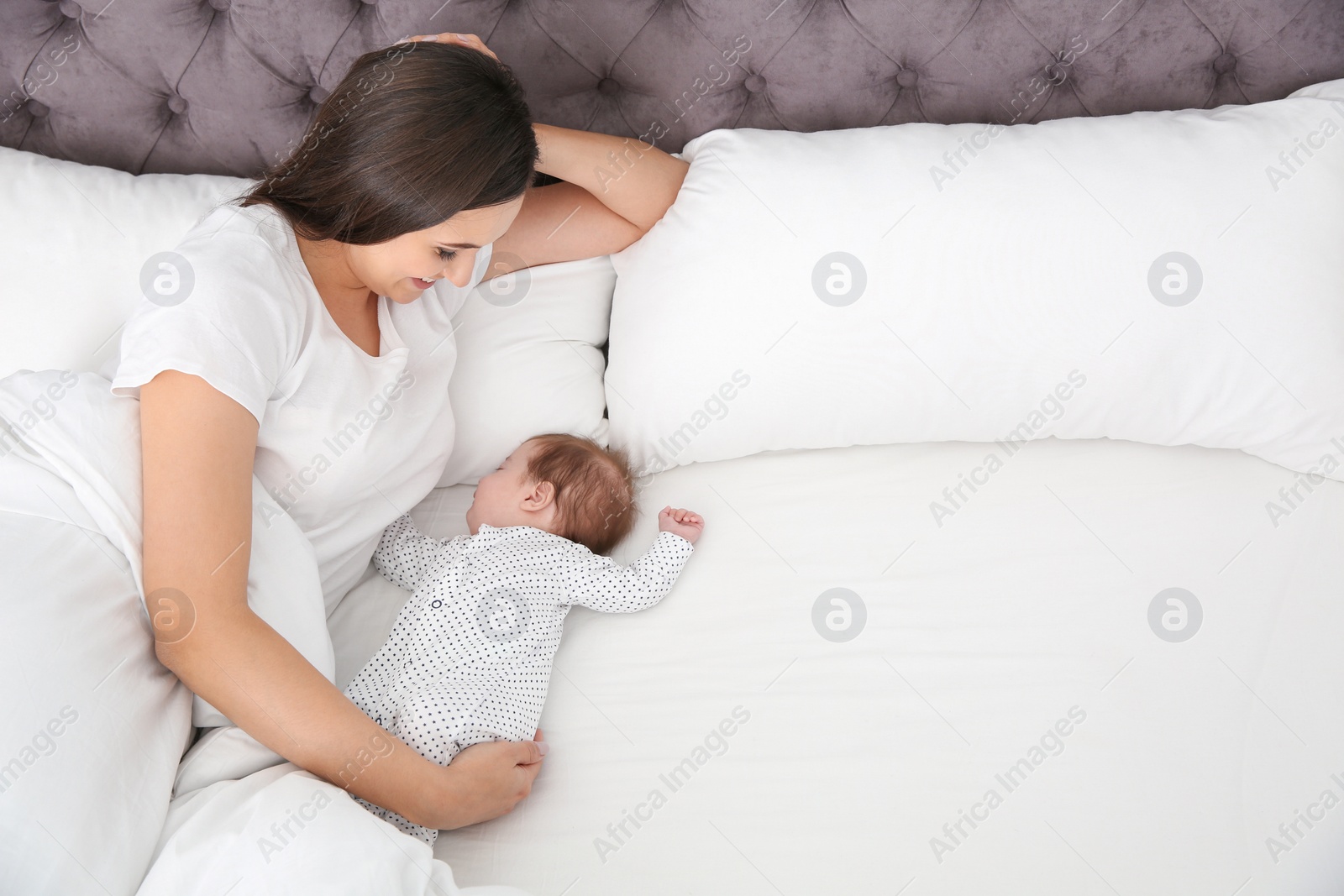 Photo of Woman with her sleeping baby on bed. Space for text