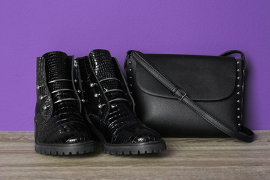 Photo of Pair of stylish ankle boots and bag on wooden background