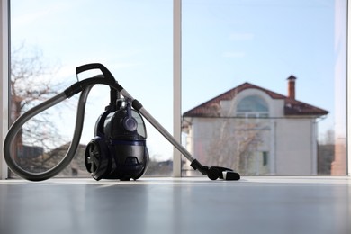 Photo of Modern vacuum cleaner near window indoors, space for text