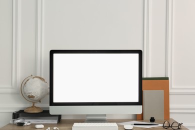 Photo of Stylish workspace with computer and stationery on wooden desk near white wall