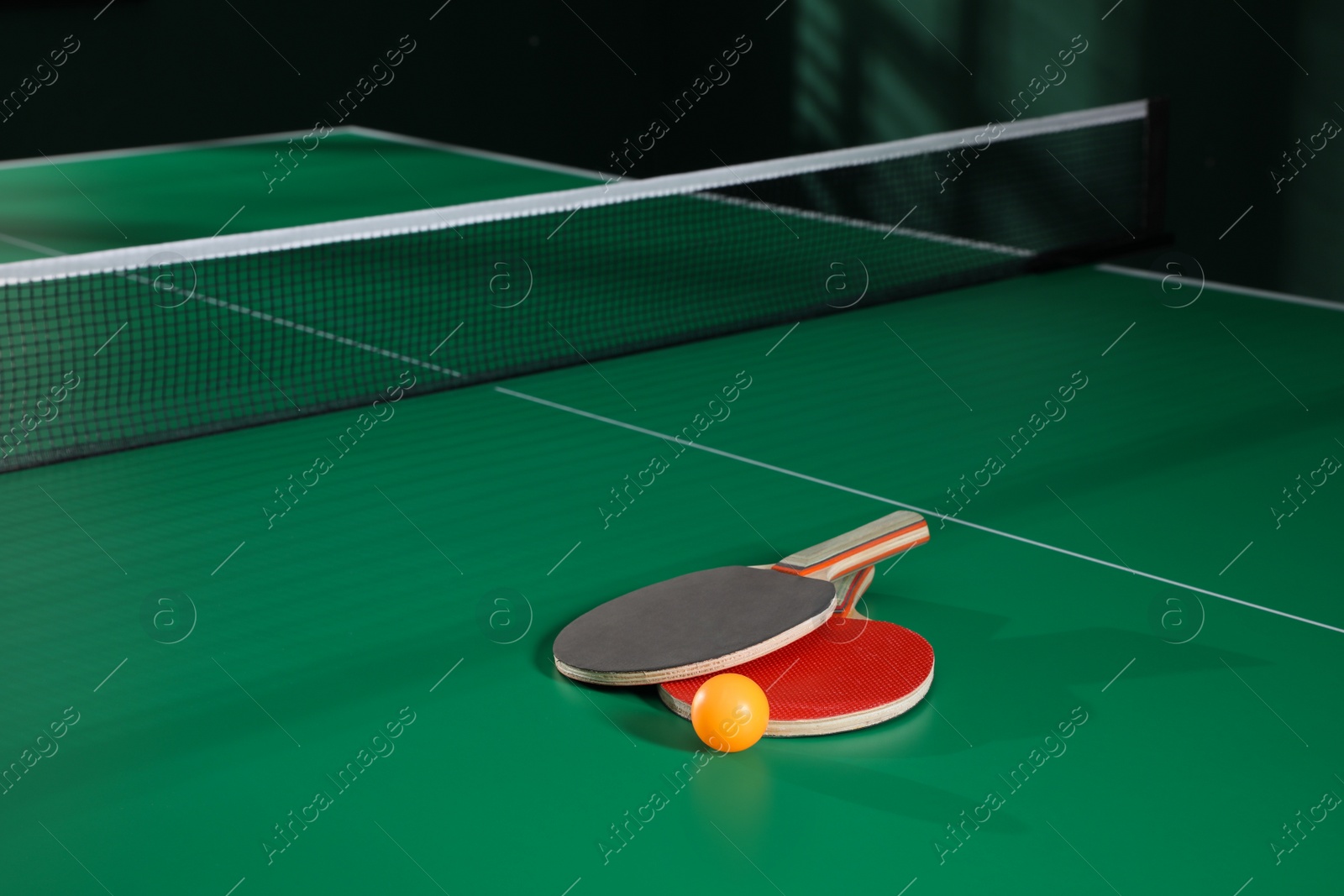 Photo of Rackets and ball on green ping pong table indoors. Space for text