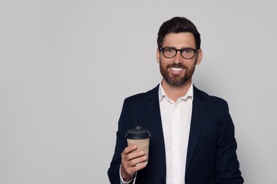 Photo of Smiling bearded man with glasses and paper cup on light grey background. Space for text