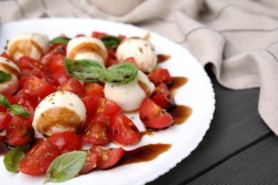 Tasty salad Caprese with tomatoes, mozzarella balls, basil and balsamic vinegar on grey wooden table, closeup