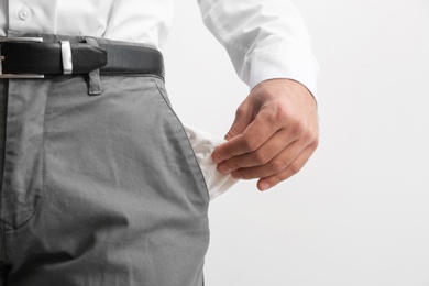 Photo of Businessman showing empty pocket on light background, closeup