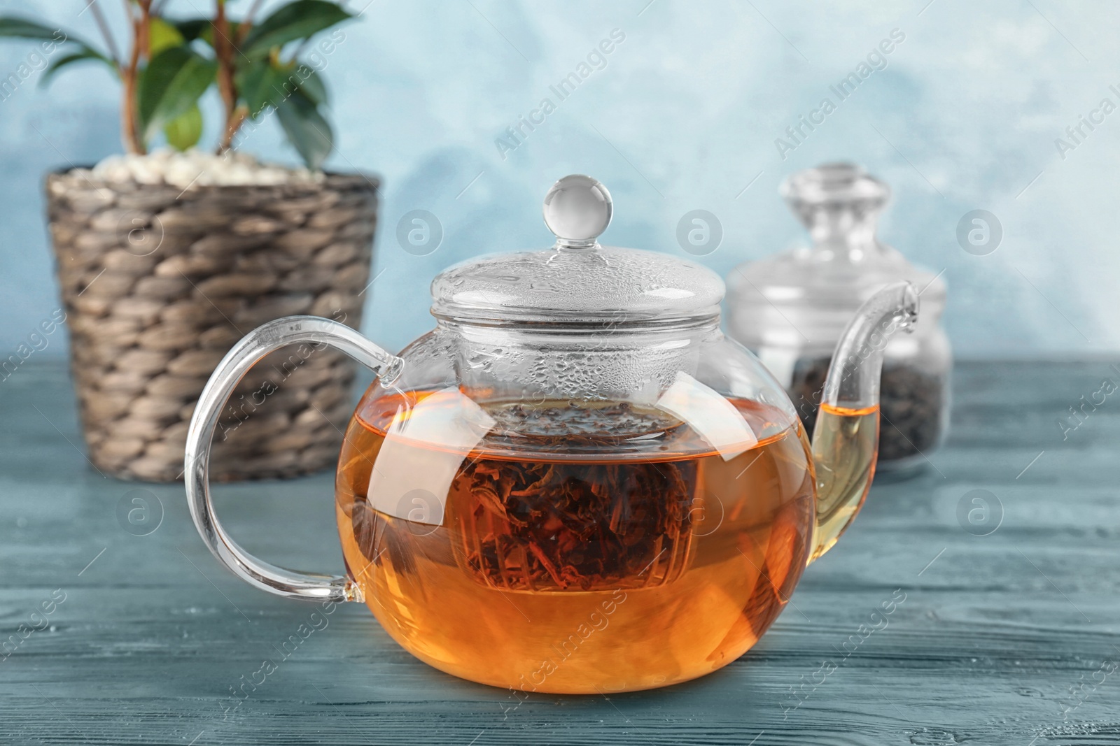 Photo of Glass pot with hot aromatic tea and shrub on table