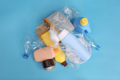 Pile of plastic garbage on light blue background, flat lay