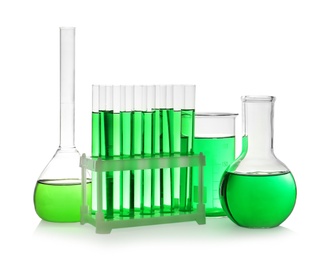 Laboratory glassware with green liquid on white background