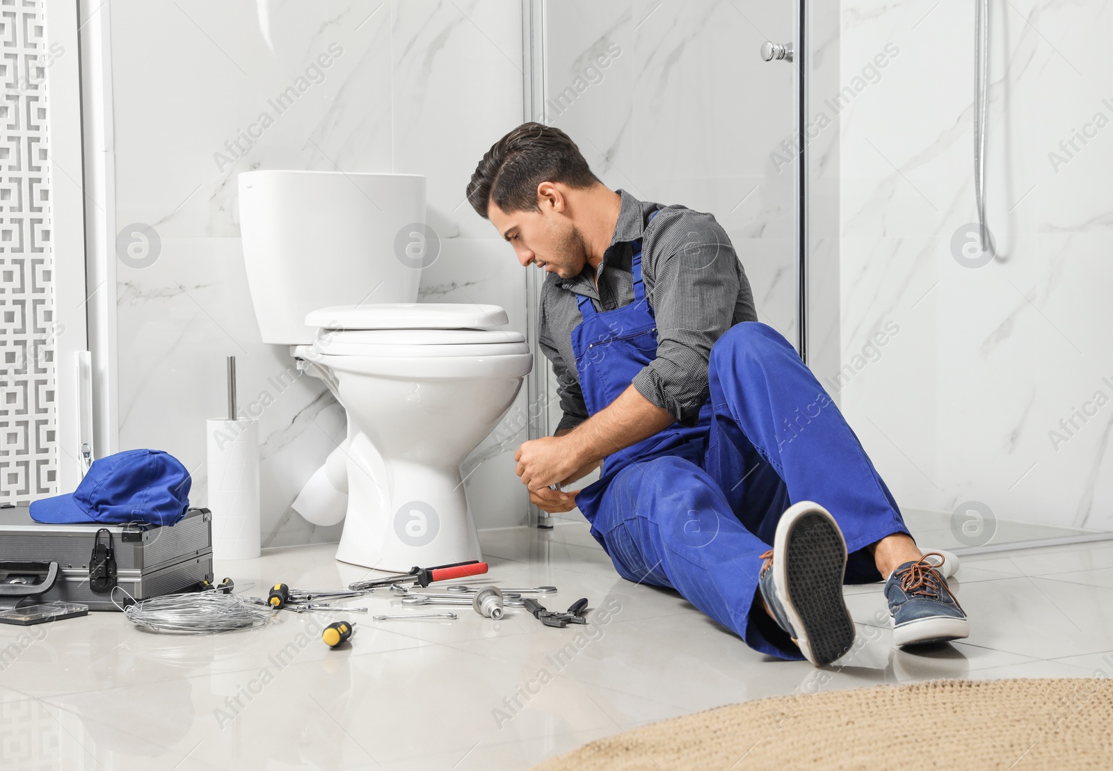 Photo of Professional plumber working with toilet bowl in bathroom