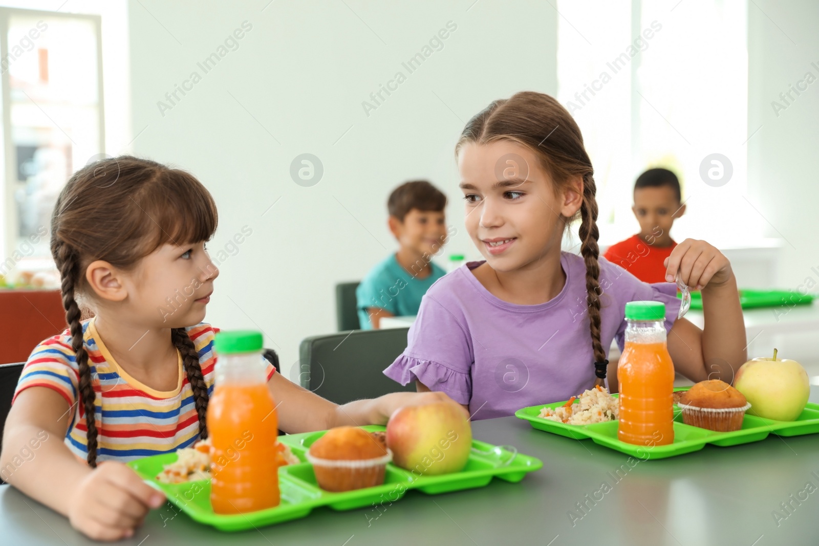 Photo of Children sitting at table and eating healthy food during break at school