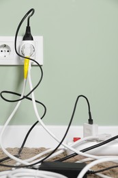 Photo of Different electrical plugs in socket and power strip on floor indoors. Space for text