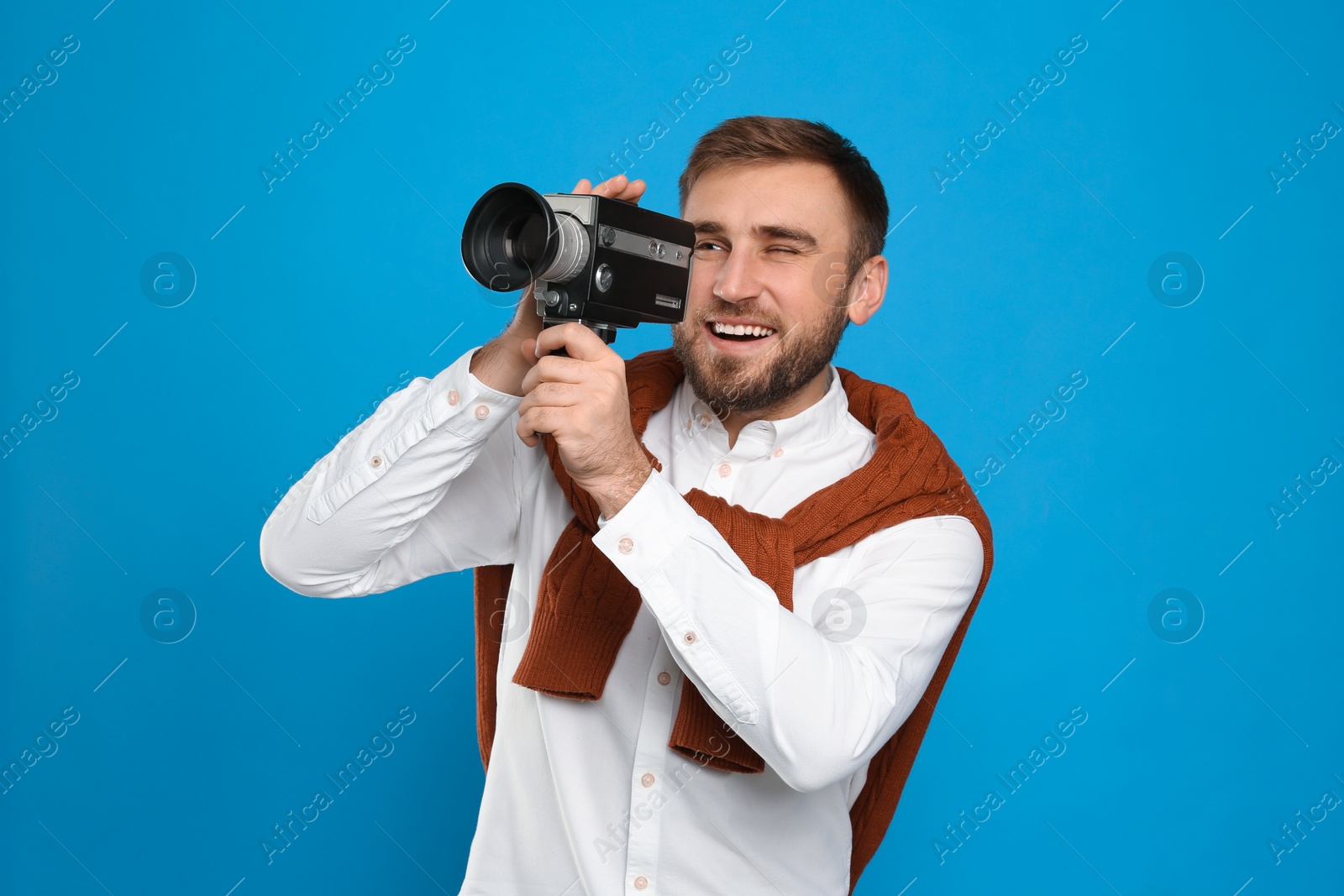 Photo of Young man with vintage video camera on light blue background