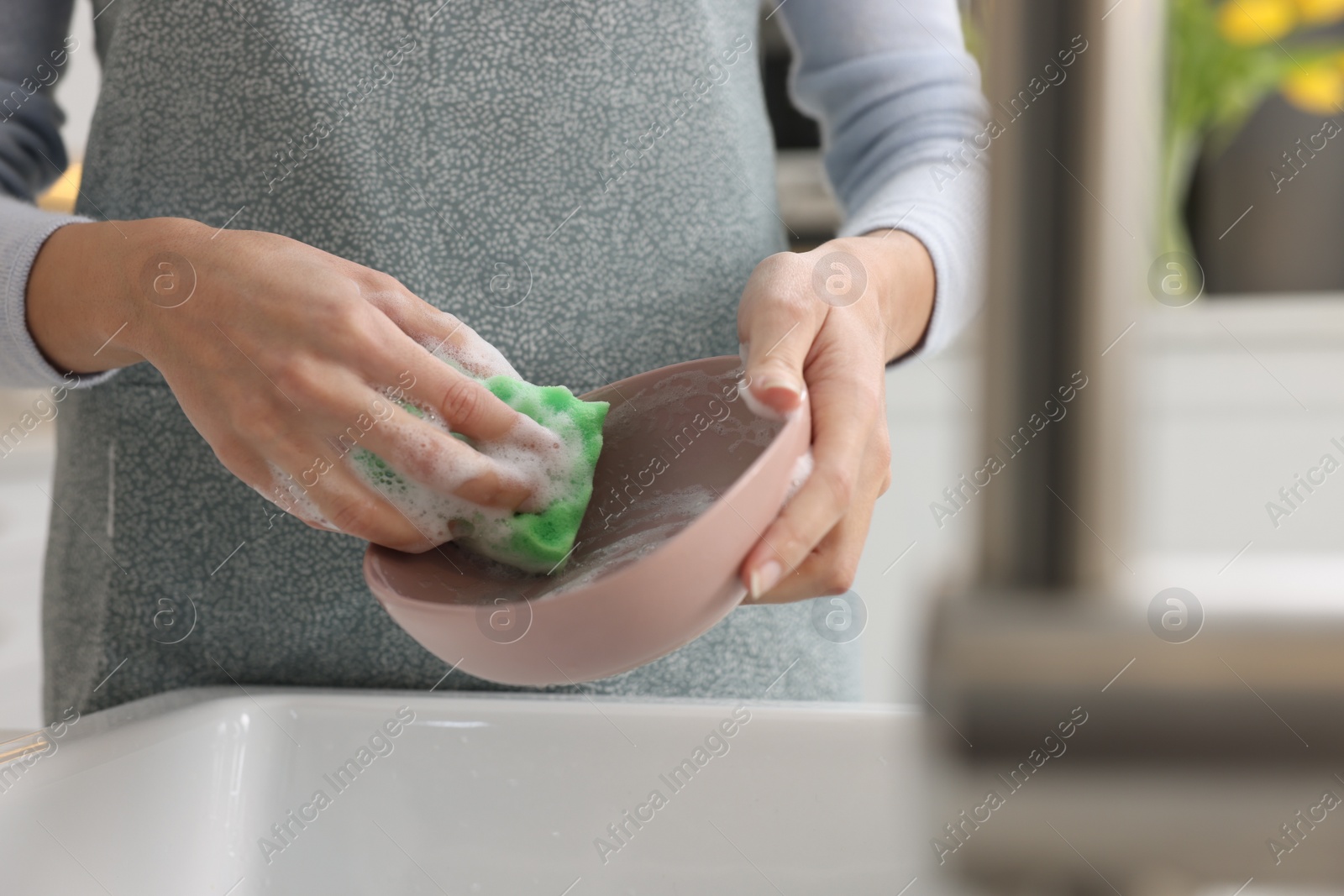 Photo of Woman washing plate above sink in modern kitchen, closeup