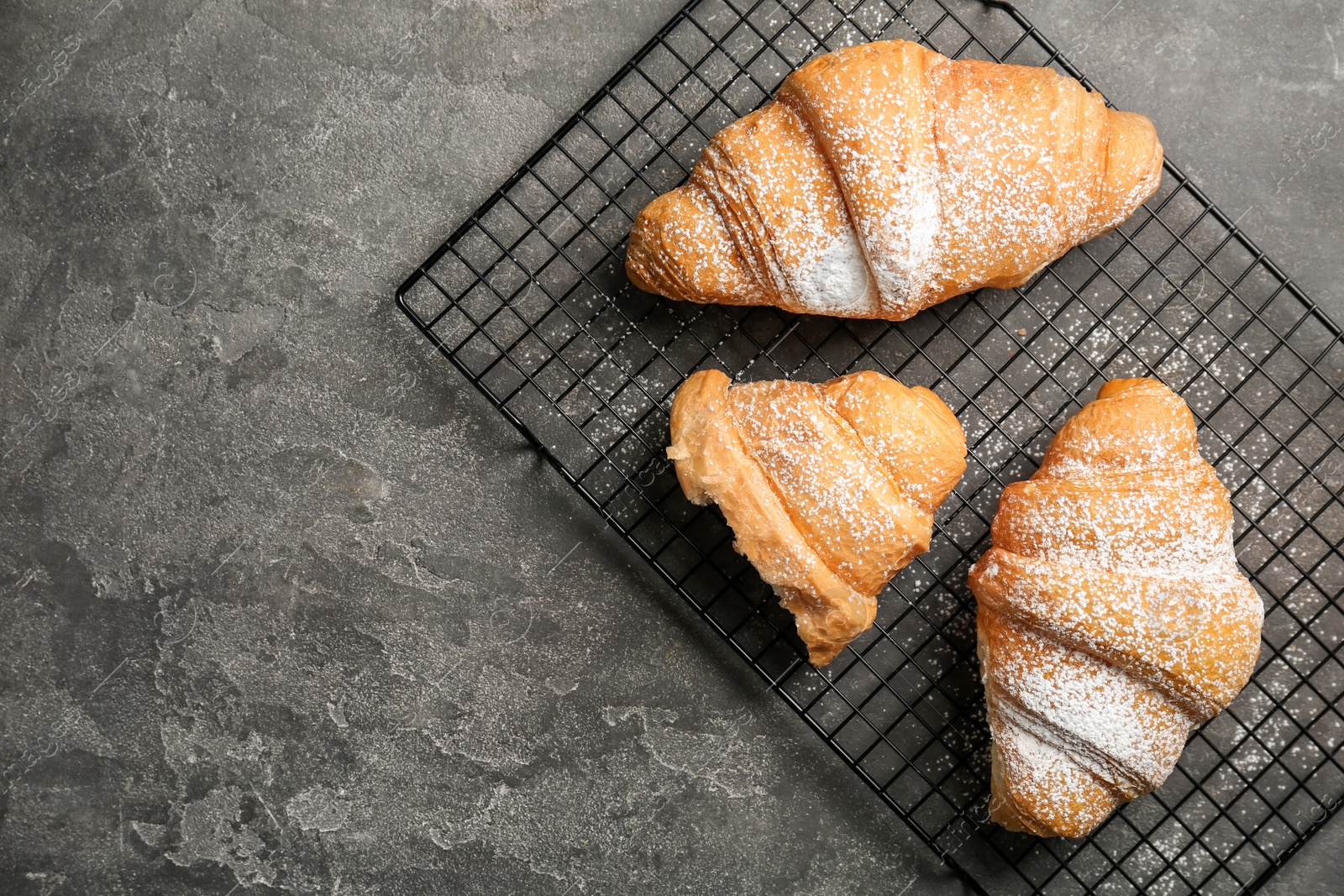 Photo of Tasty croissant with sugar powder on gray background, top view