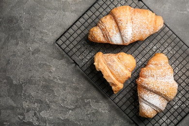 Tasty croissant with sugar powder on gray background, top view