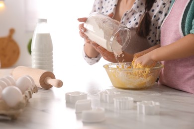 Photo of Mother and daughter making dough at table in kitchen, closeup